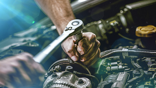 close up of hand with wrench in hand working on an engine
