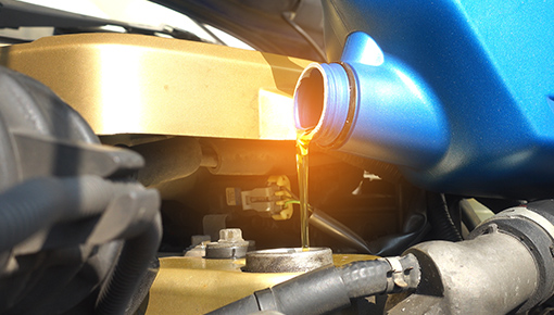 service member pouring oil into a car